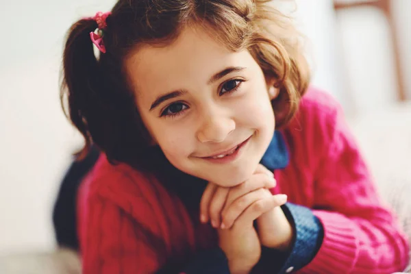 Очаровательная маленькая девочка со сладкой улыбкой лежит на кровати . — стоковое фото