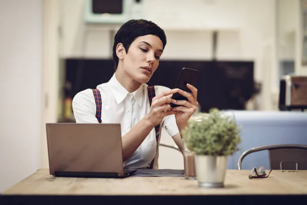 Young businesswoman with very short haircut looking at her smart — Stock Photo, Image