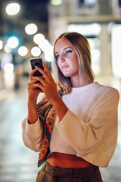 Жінка фотографує зі смартфоном вночі на вулиці — стокове фото