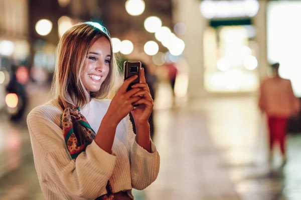 Γυναίκα λήψη φωτογραφίας με smartphone το βράδυ στο δρόμο — Φωτογραφία Αρχείου
