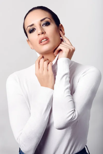 Jonge brunette vrouw dragen witte poloneck in studio schot — Stockfoto