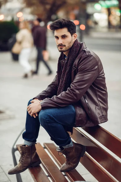 Nachdenklicher junger Mann sitzt auf einer städtischen Bank. — Stockfoto