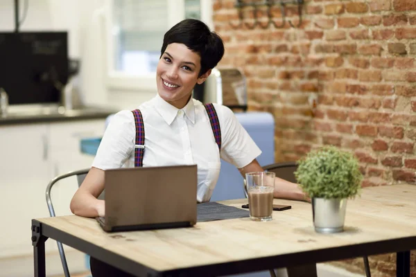 Ung kvinna med mycket kort frisyr att skriva med en bärbar dator hemma — Stockfoto