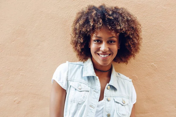 Jonge zwarte vrouw, die afro kapsel, lacht in stedelijke achtergrond — Stockfoto