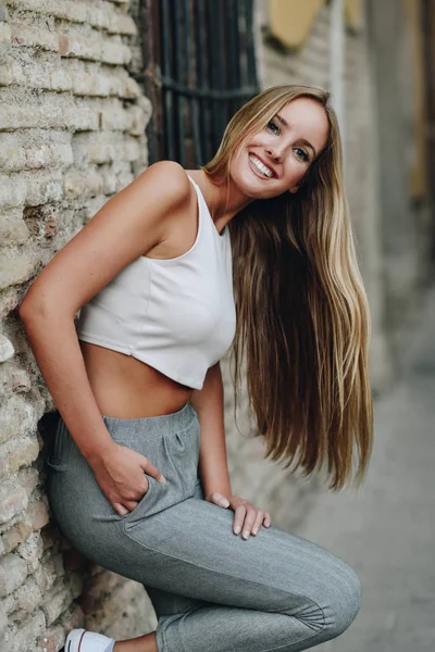 Lachende blond meisje met rechte haren in de stedelijke achtergrond — Stockfoto