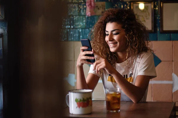 Arabische lachende vrouw in een prachtige bar kijken naar haar smartphon — Stockfoto