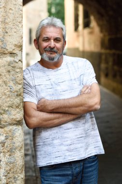 Olgun adam kamera kentsel arka planda bakarak gülen