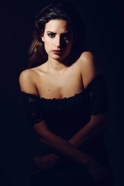Young brunette woman in black lingerie in chiaroscuro lighting clipart
