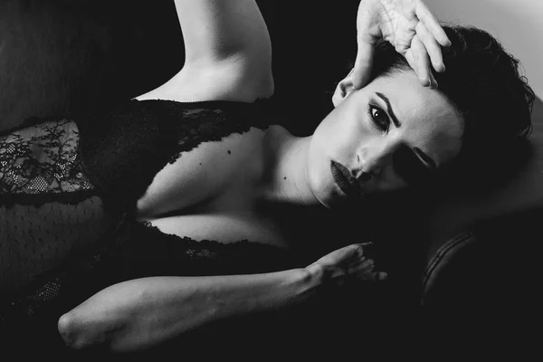 Vacker kvinna i svart underkläder på en soffa — Stockfoto