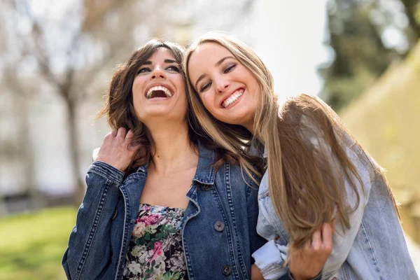 Två glada unga kvinnor vänner kramar i gatan. — Stockfoto