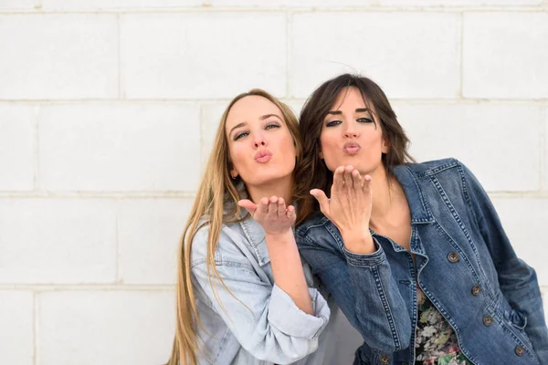 Deux jeunes femmes soufflant un baiser sur un mur urbain . — Photo