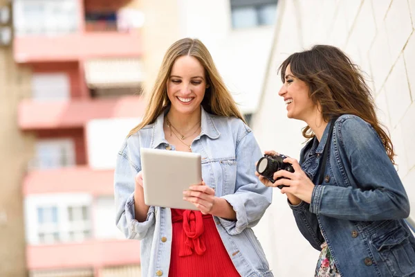 Dos mujeres turísticas jóvenes que buscan mapas con tableta digital al aire libre — Foto de Stock