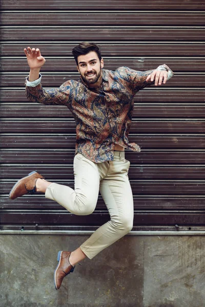 Joven barbudo saltando en el fondo urbano con los brazos abiertos wea — Foto de Stock