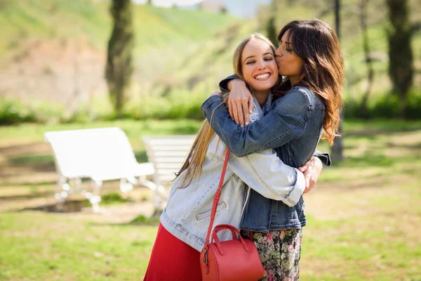 Jovem mulher beijando seu amigo rosto ao ar livre — Fotografia de Stock