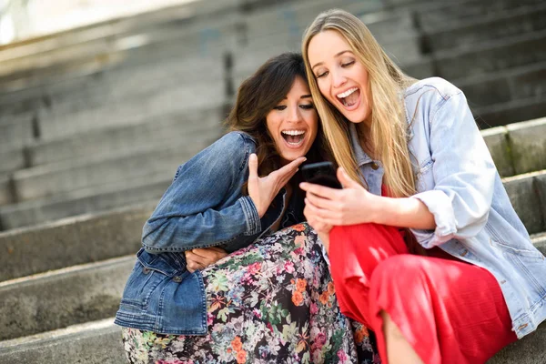 그들의 스마트 폰에 몇 가지 재미 있는 것을 보고 하는 두 여자 — 스톡 사진