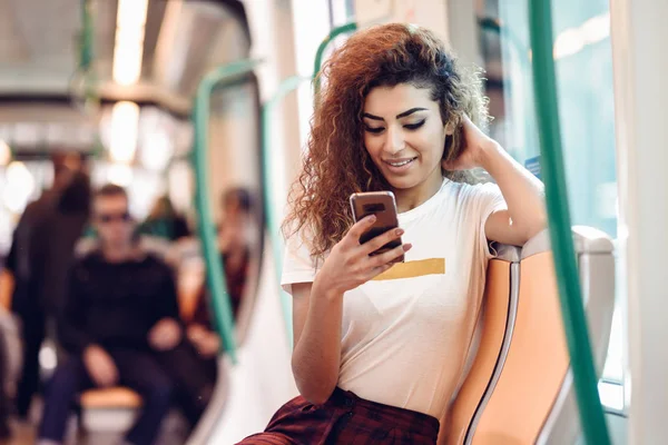 Araberin in U-Bahn blickt auf ihr Smartphone — Stockfoto