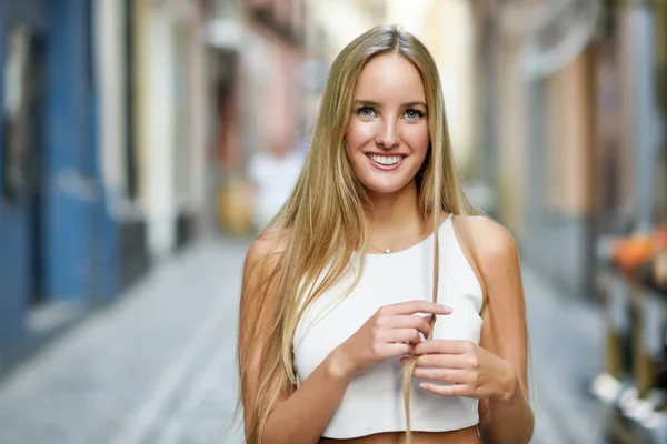 Beautiful young blonde woman smiling in urban background. — Stock Photo, Image