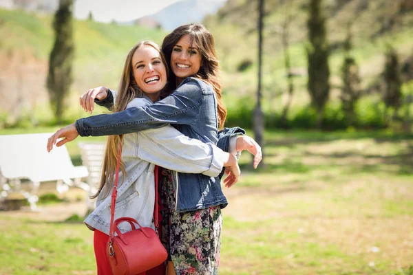 Kent parkta sarılma iki mutlu genç kadın arkadaş. — Stok fotoğraf