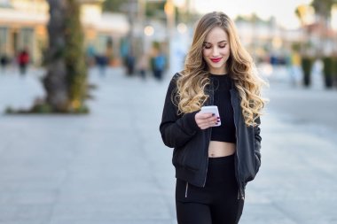 Sarışın kadın manifatura ile onun smartphone kentsel arka planda