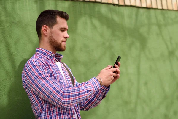 年轻男子看着他的智能手机在城市背景。Lifest — 图库照片