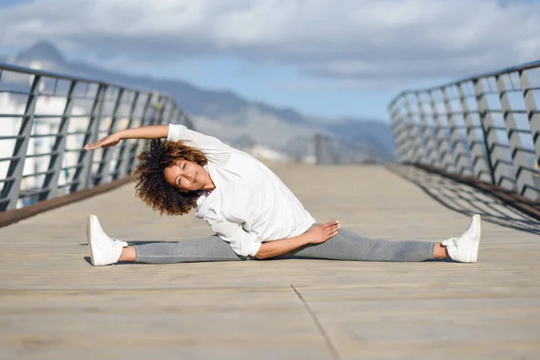 Молодая черная женщина делает растяжку после бега на открытом воздухе — стоковое фото