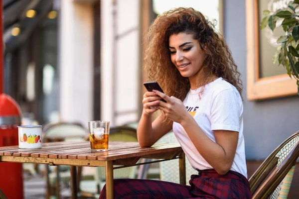 Arabische vrouw in een stedelijke bar bij haar smartphone. — Stockfoto