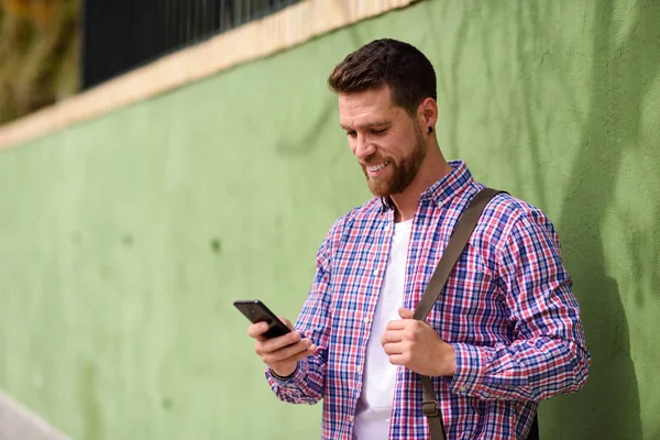 Joven mirando su teléfono inteligente en el fondo urbano. Lifest — Foto de Stock