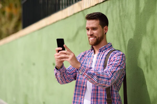 Joven mirando su teléfono inteligente en el fondo urbano. Lifest — Foto de Stock