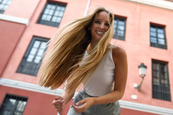 Mujer joven feliz con el pelo en movimiento en el fondo urbano . — Foto de Stock