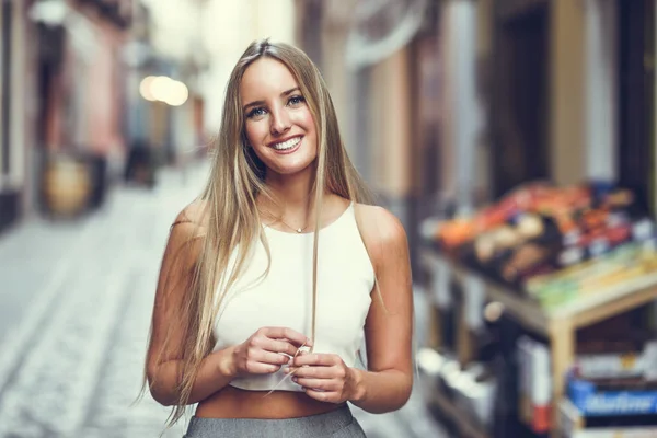 Belle jeune femme blonde souriante en fond urbain . — Photo