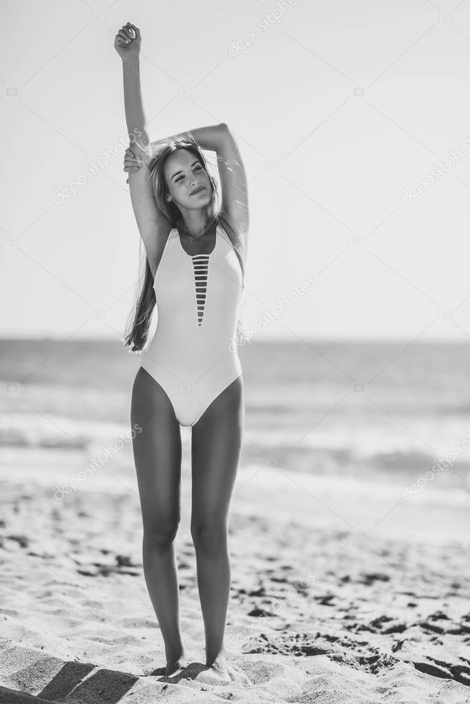 Blond woman with beautiful body in swimswit on a tropical beach