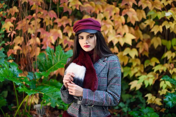 Joven hermosa chica con el pelo muy largo con abrigo de invierno y gorra en el fondo de las hojas de otoño — Foto de Stock