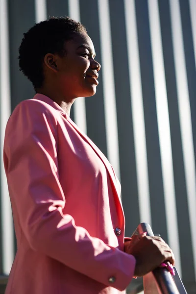 Sonriente mujer de negocios negro de pie cerca de edificio de oficinas de negocios — Foto de Stock