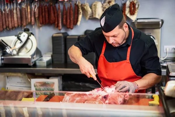 Butcher boning fresh ham in a modern butcher shop — Stock Photo, Image