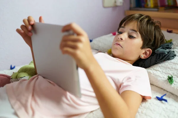 Menina bonito usando um computador tablet em seu quarto — Fotografia de Stock