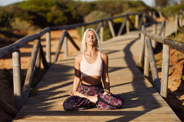 Mujer caucásica practicando yoga en puente de madera . — Foto de Stock