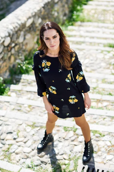 Middle-aged woman wearing flowered dress in urban steps. — Stock Photo, Image