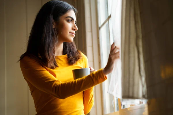 Perska kobieta pijąca kawę patrząc przez okno — Zdjęcie stockowe