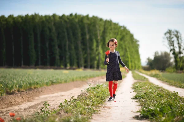 Маленькая девочка ходит по полю природы в красивом платье — стоковое фото