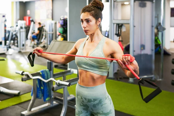 Junge Sportlerin wärmt sich mit Fitnessgummis im Fitnessstudio auf — Stockfoto