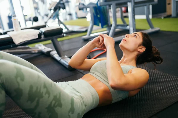 Ung idrottskvinna på yogamatta gör situps i gymmet. — Stockfoto