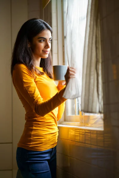 Persisk kvinna dricker kaffe medan du tittar genom fönstret — Stockfoto