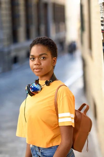 Jeune femme africaine portant des vêtements décontractés et écouteurs regardant la caméra — Photo