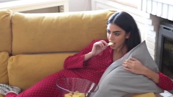 Persian woman at home watching TV eating chips potatoes — 비디오
