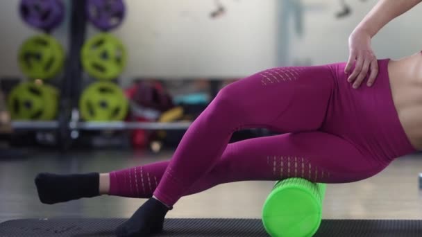 Woman relaxing her leg muscles with a green foam roller — Stock Video