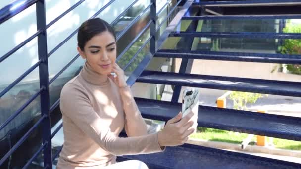 Perski kobieta za pomocą smartfona siedzi na miejskich schodach — Wideo stockowe