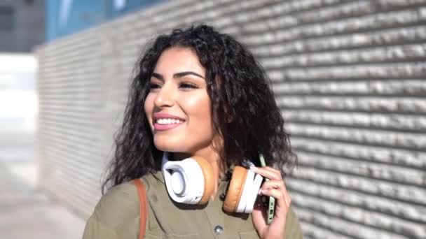 Mujer árabe joven caminando por la calle con auriculares — Vídeos de Stock