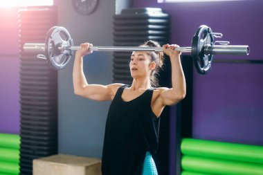 Spor salonundaki atletik kadın ağırlık kaldırıyor.