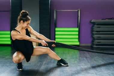 Genç ve atletik bir kadın spor salonunda ip kullanıyor..