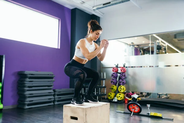 Atletische vrouw doet hurken op box in de sportschool — Stockfoto